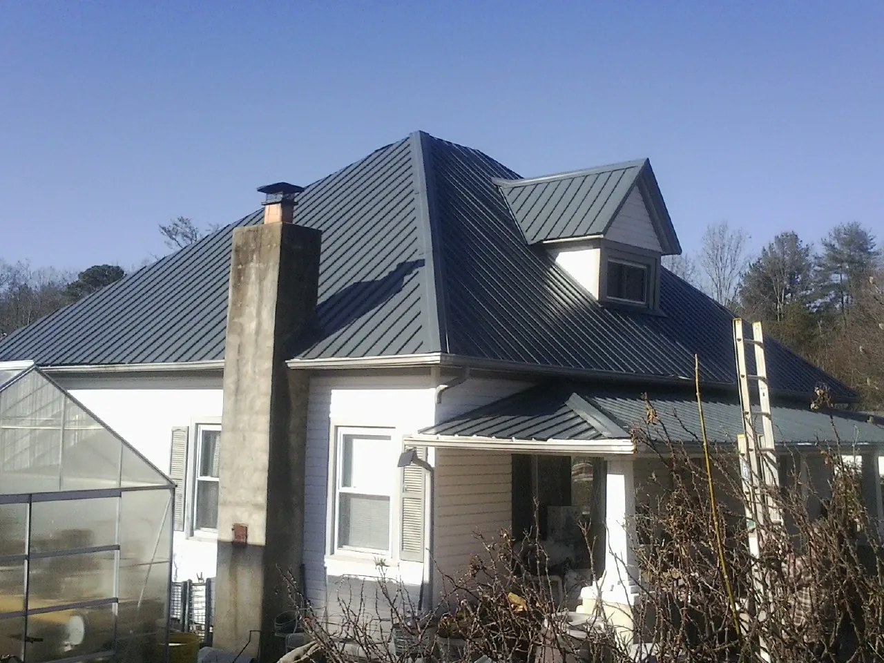 Dark blue standing seam metal roof on a white farmhouse with dormer — Slate & Tile Roof Repair by Roofing Brothers in Rushsylvania