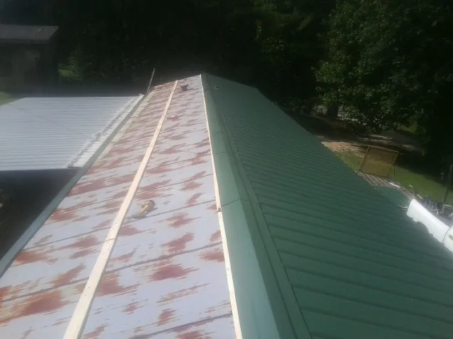 Old rusted panels beside newly installed green metal roofing — Wind Damage Roof Repair by Roofing Brothers in Rushsylvania