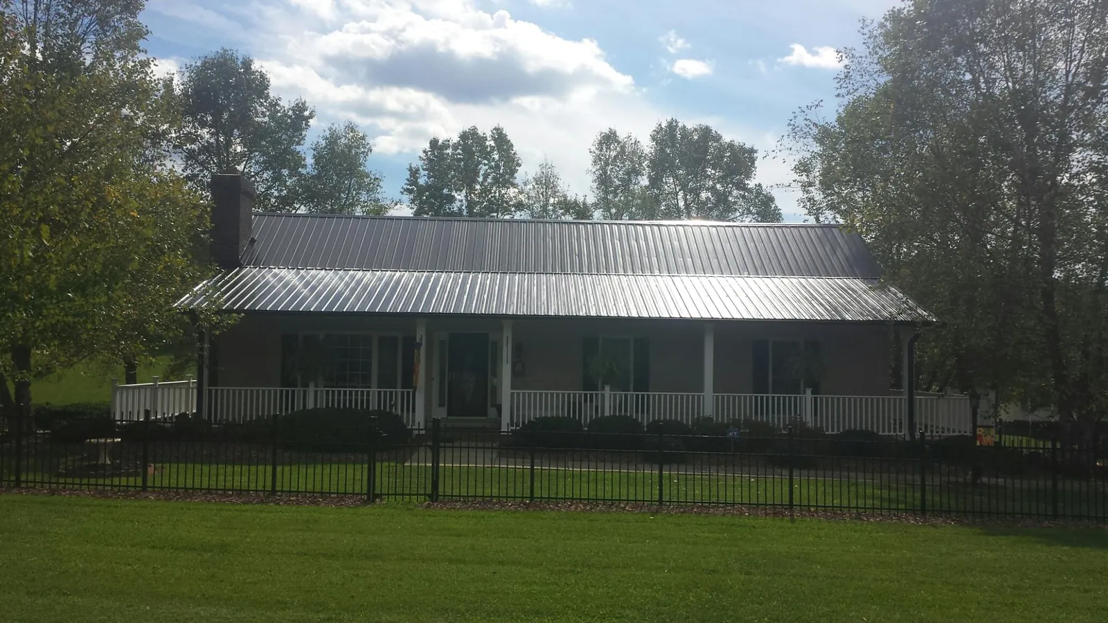 Gray metal roof on a brick ranch with a full width front porch — Gutter Guard Installation work by our crew in Rushsylvania