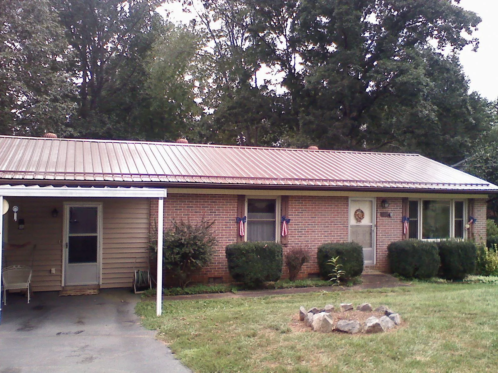 Bronze metal roof and carport on a brick ranch home — Roof Repair work by our crew in Rushsylvania