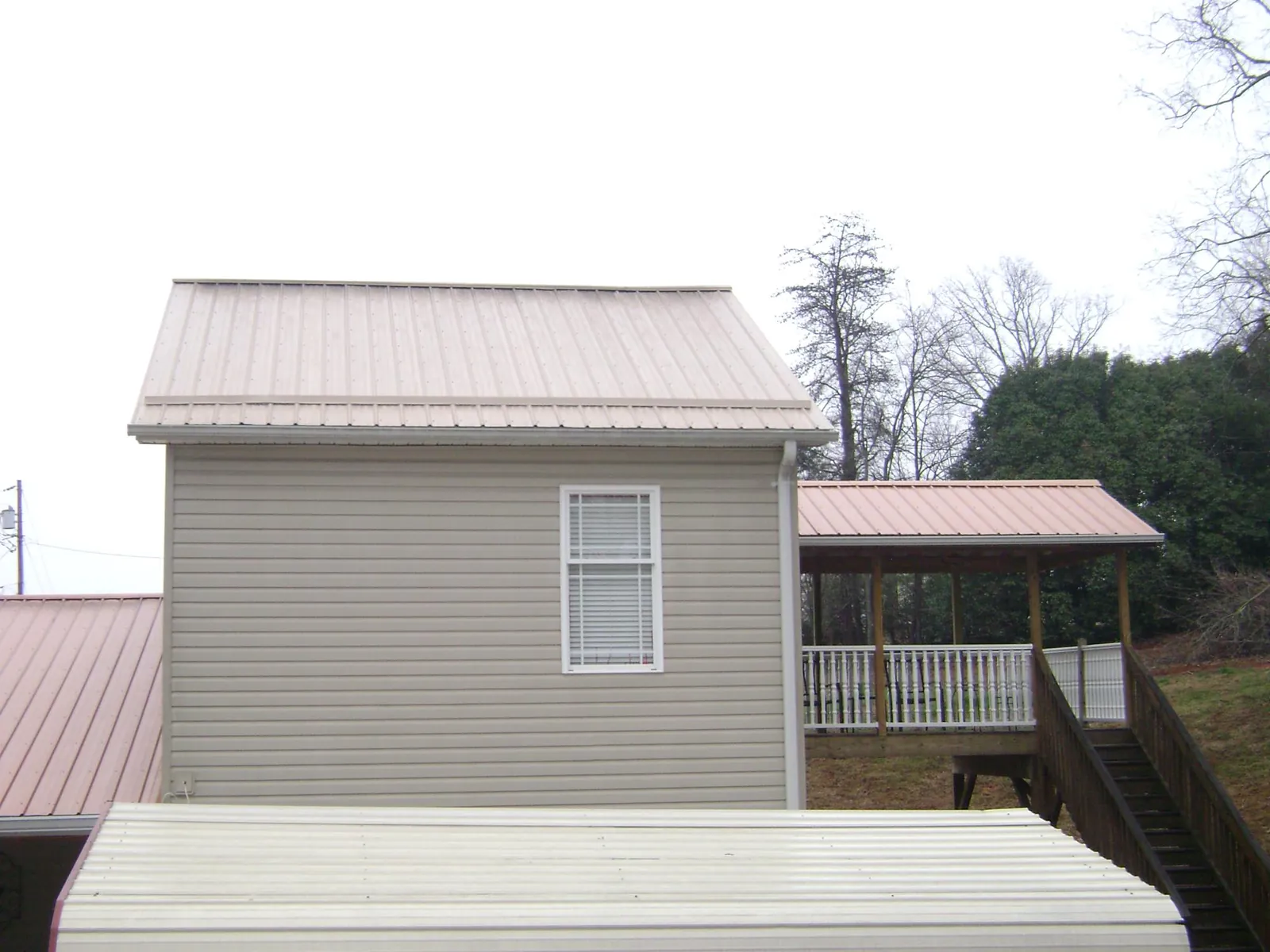 Tan metal roofs on a two story addition and attached porch, from a Roof Replacement job in Rushsylvania