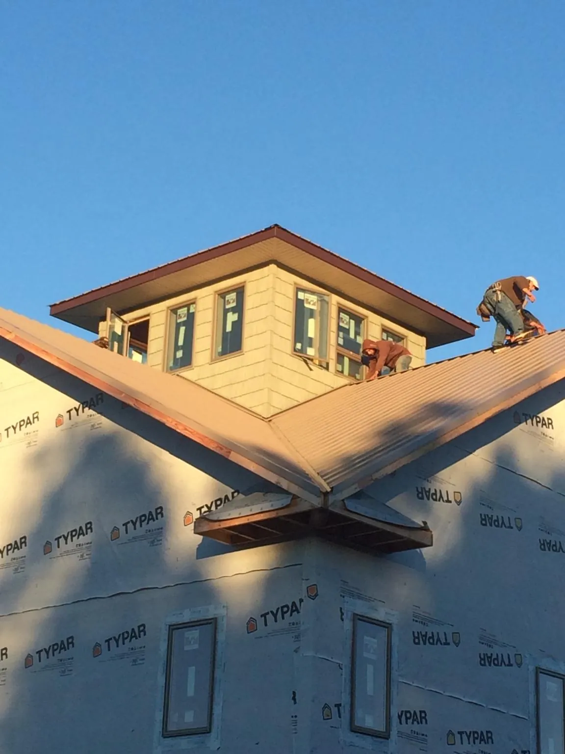 Roofers working around a rooftop cupola on a new metal roof at sunset — Roof Waterproofing in Rushsylvania by Roofing Brothers